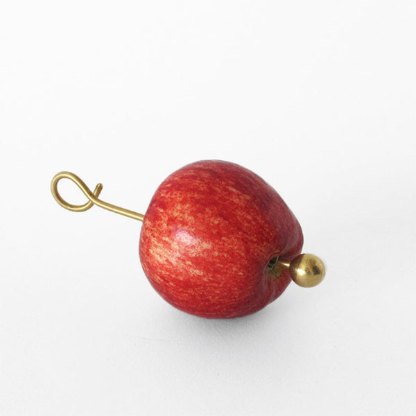 Brass apple feeder with apple on it on white background
